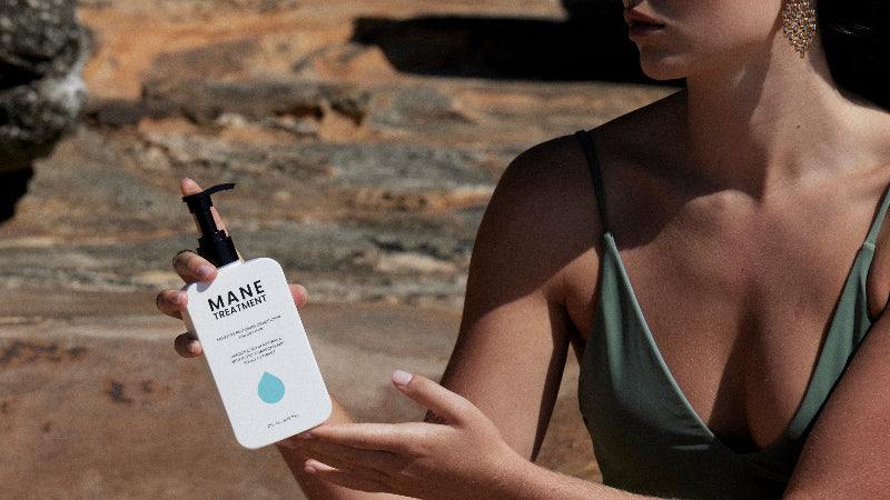 Model holding Mane Treatment moisture restoring, hair growth promoting conditioner by Hub for Belle