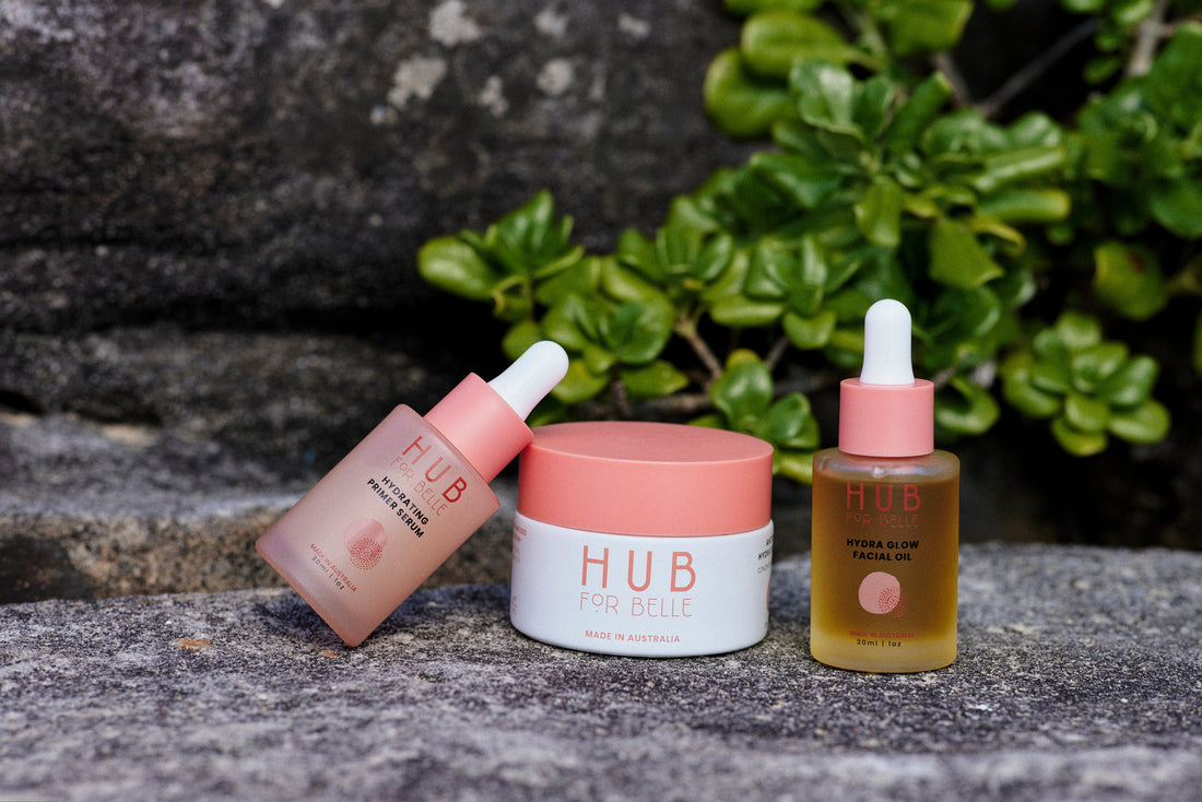Hub for Belle serum, face cream and facial oil laid out on warm sandstone with Kakadu Plum fruit