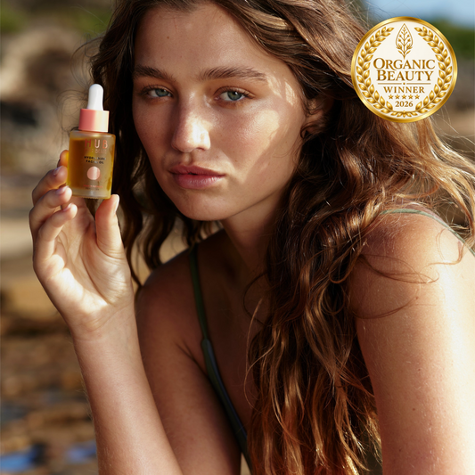 Model holding to face a bottle of Hub for Belle award winning natural Hydra Glow Facial oil balancing made with vegan Australian botanicals for glowing skin from Hub for Belle. A gold medal Winner Organic Beauty Winner 2026.